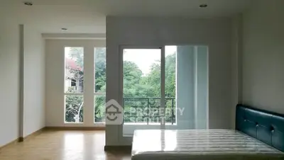 Spacious bedroom with large windows and balcony access, offering serene green views.