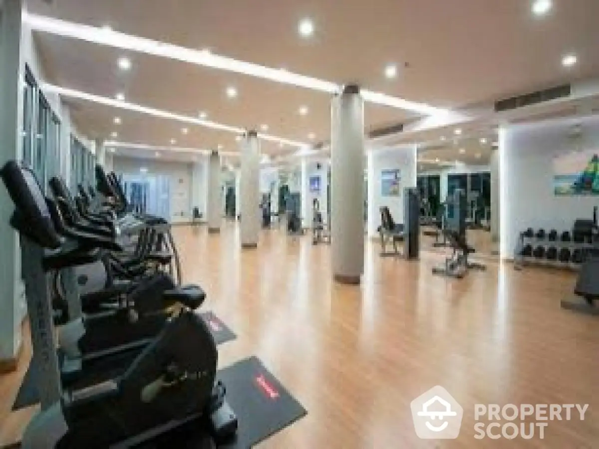 Spacious modern gym with state-of-the-art equipment and sleek wooden flooring.