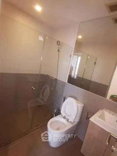 Modern bathroom with glass shower and sleek fixtures in contemporary apartment.