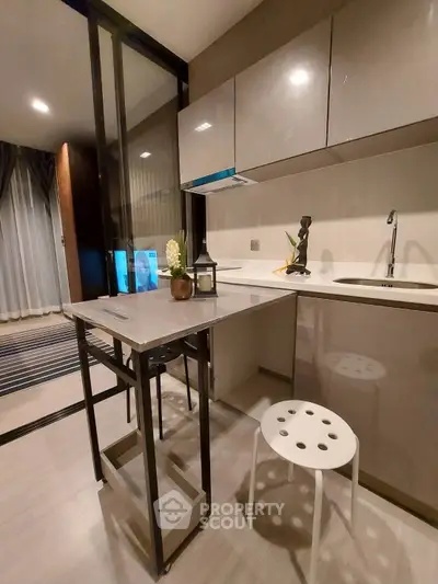 Modern kitchen with sleek cabinets and compact dining area in stylish apartment