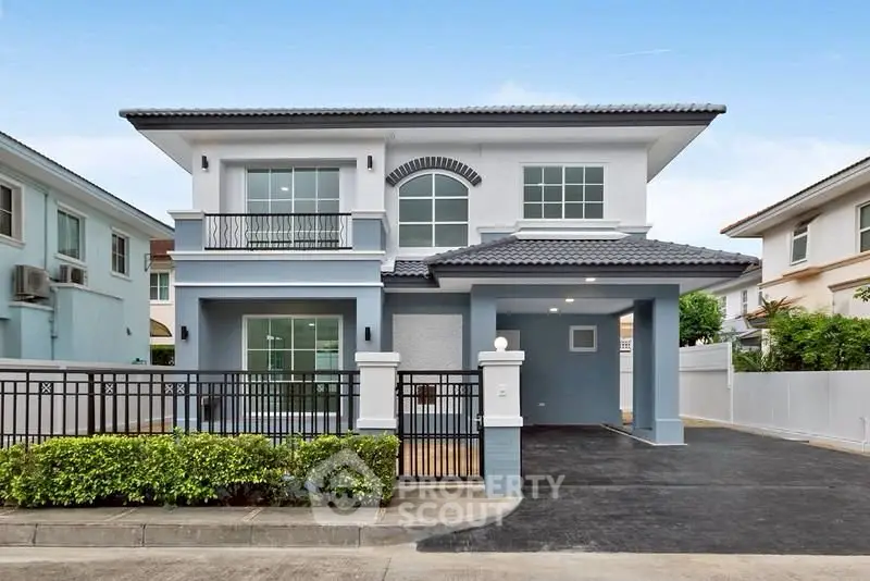 Modern two-story house with sleek design and spacious driveway in suburban neighborhood.