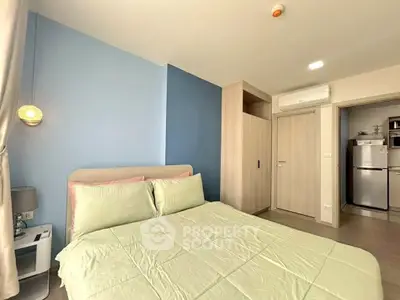 Modern bedroom with stylish decor and built-in wardrobe, featuring air conditioning and a glimpse of the kitchen.