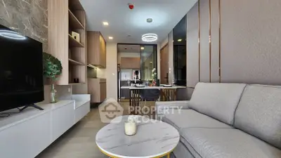 Modern living room with open kitchen, stylish decor, and cozy seating area.