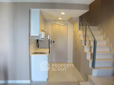Modern compact kitchen with sleek staircase in stylish apartment