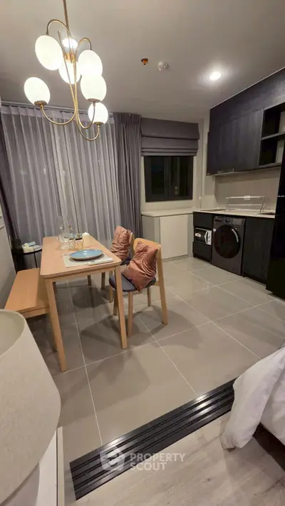 Modern kitchen with dining area featuring sleek cabinetry and stylish lighting.