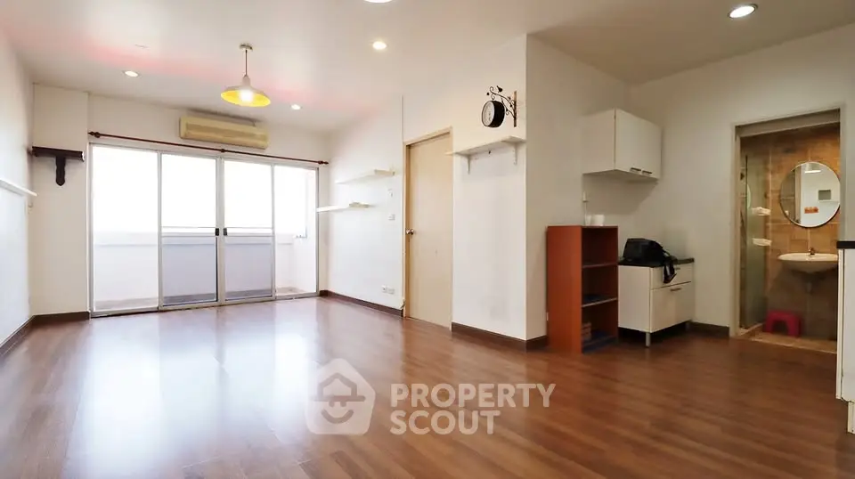 Spacious open-plan living area with wooden flooring and balcony access