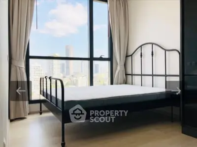 Bright bedroom with large window offering stunning city views and modern metal bed frame.