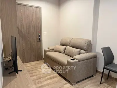 Cozy living room with modern sofa and flat-screen TV, perfect for relaxation.