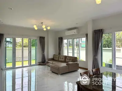 Spacious living room with modern sofa and large windows offering garden view