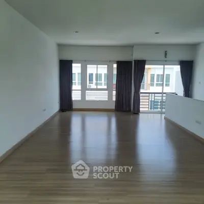 Spacious empty living room with large windows and balcony access, perfect for customization.