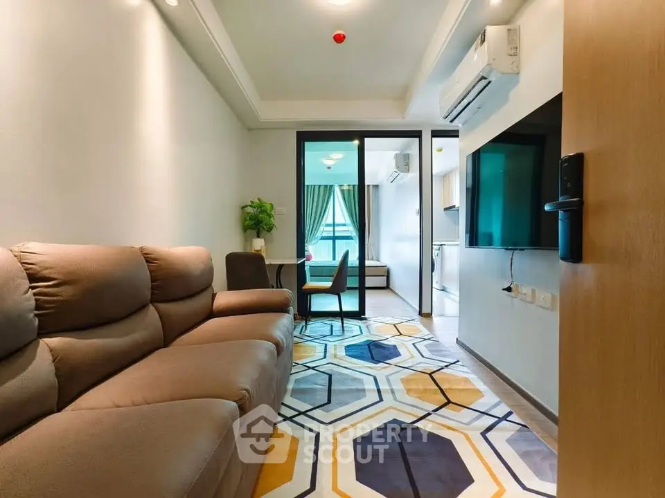 Modern living room with stylish decor and open layout, featuring a cozy sofa and vibrant geometric rug.