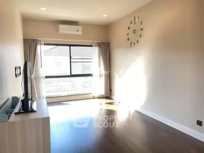 Spacious living room with modern decor and large window offering natural light.