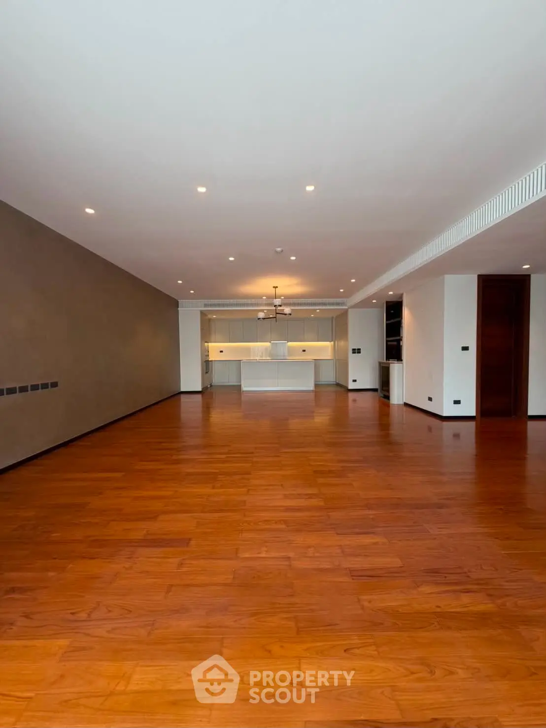 Spacious open-plan living room with wooden flooring and modern kitchen.