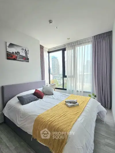 Modern bedroom with city view, featuring stylish decor and natural light through large windows.