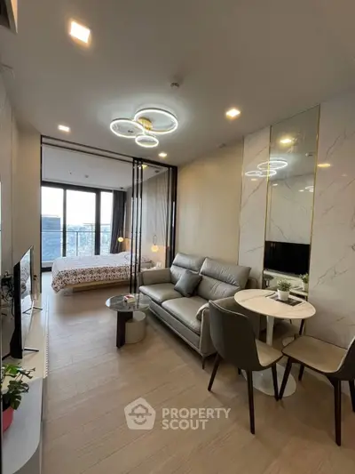 Modern open-plan living room with stylish furniture and a view of the bedroom in a luxury apartment.