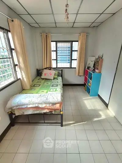 Cozy bedroom with single bed and colorful storage unit, bright natural light.