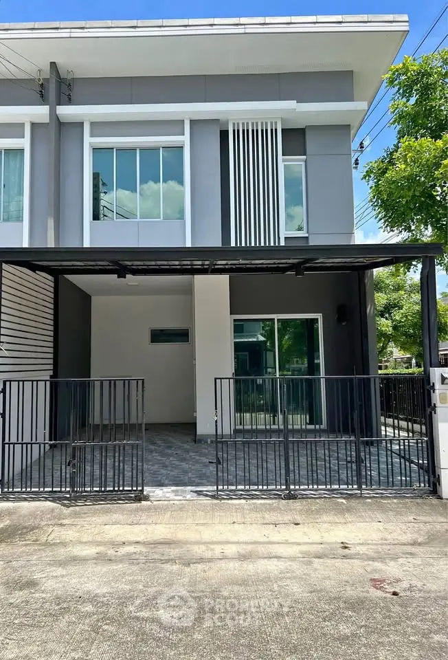 Modern townhouse exterior with sleek design and gated entrance in a suburban neighborhood.
