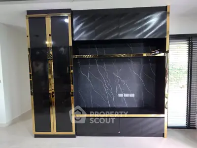 Luxurious modern living room with sleek black and gold built-in shelving unit.