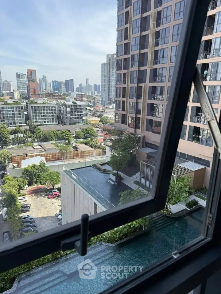 Stunning cityscape view from high-rise apartment window overlooking pool and urban skyline.