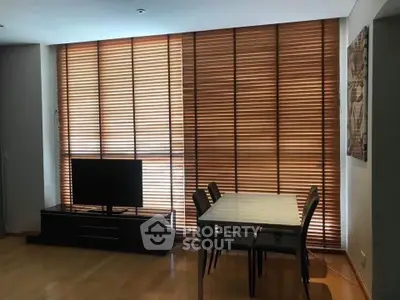Modern living room with wooden blinds, sleek TV stand, and dining table for four.