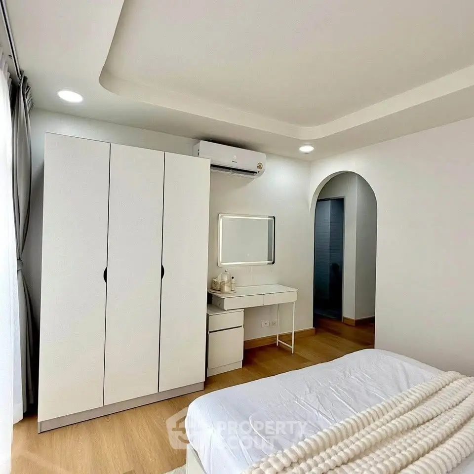 Modern bedroom with sleek wardrobe and cozy bed in bright, airy space.