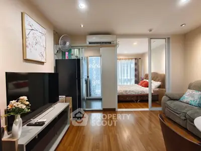 Modern living room with wooden flooring, cozy sofa, and large TV, leading to a stylish bedroom.