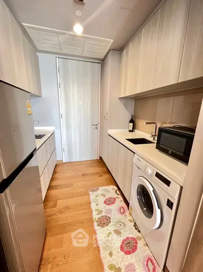 Modern kitchen with sleek appliances and wooden flooring in a compact layout.