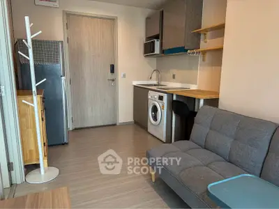 Modern studio apartment with compact kitchen and cozy living area, featuring a washing machine and stylish decor.