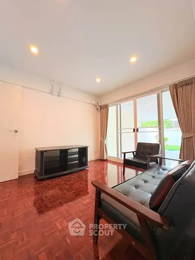 Spacious living room with elegant wooden flooring and large windows for natural light.