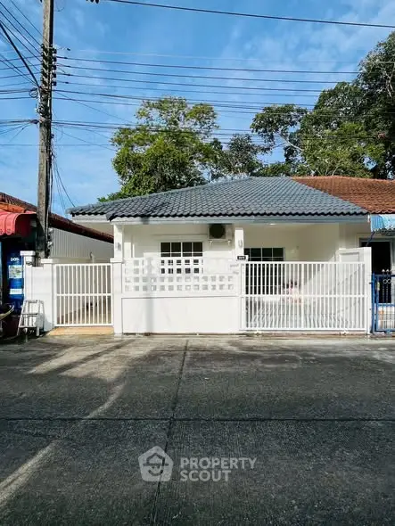 Charming single-story house with white fence and tiled roof in a quiet neighborhood.