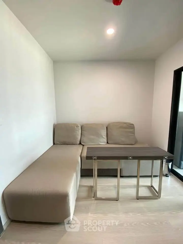 Modern minimalist living room with beige sectional sofa and sleek coffee table.