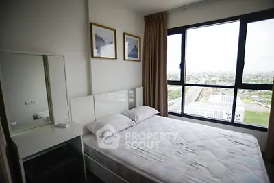 Cozy bedroom with large window offering stunning city views, perfect for relaxation and comfort.