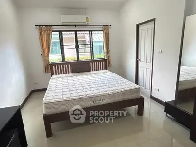 Spacious bedroom with large window and modern furnishings in a cozy home.