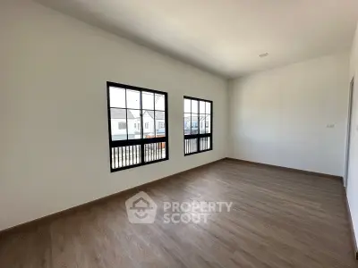 Spacious empty room with large windows and wooden flooring in modern home