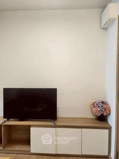 Modern living room with sleek TV stand and decorative flowers, perfect for cozy relaxation.