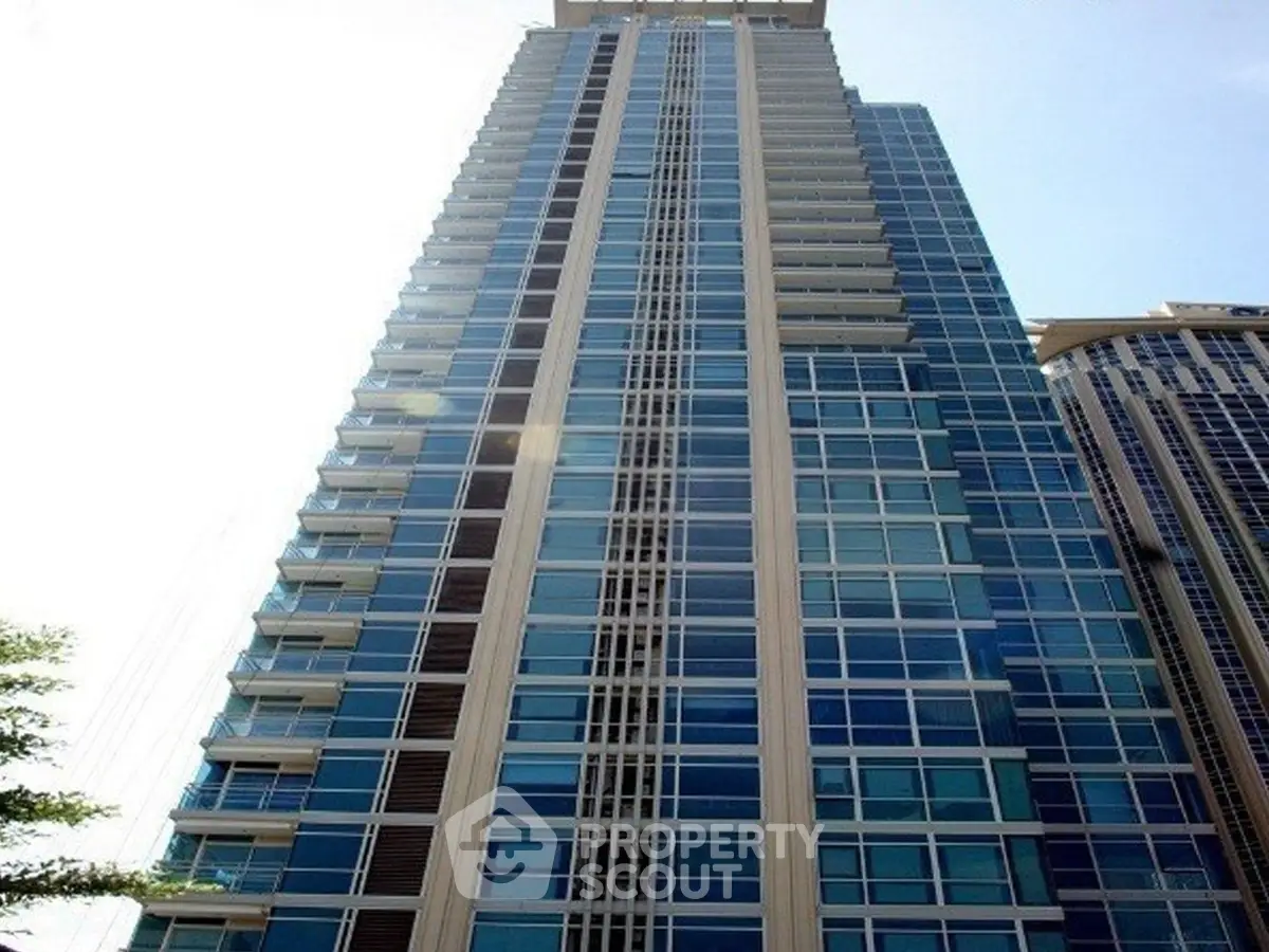 Stunning high-rise building with modern glass facade and multiple balconies in urban setting.