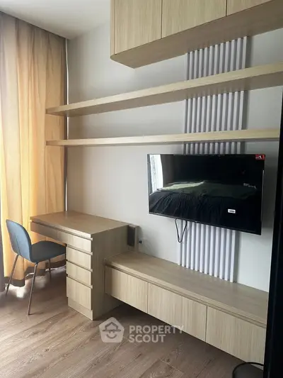 Modern study room with built-in desk, shelves, and wall-mounted TV in a stylish apartment.