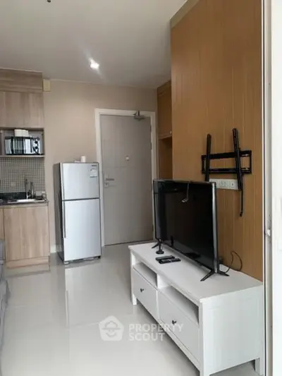 Modern apartment interior with sleek kitchen and cozy living area featuring a mounted TV.