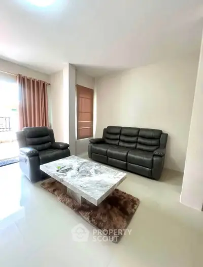 Spacious living room with modern leather sofas and marble coffee table, perfect for relaxation.