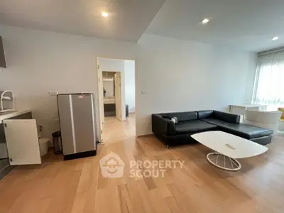 Spacious modern living room with sleek black sofa and wooden flooring