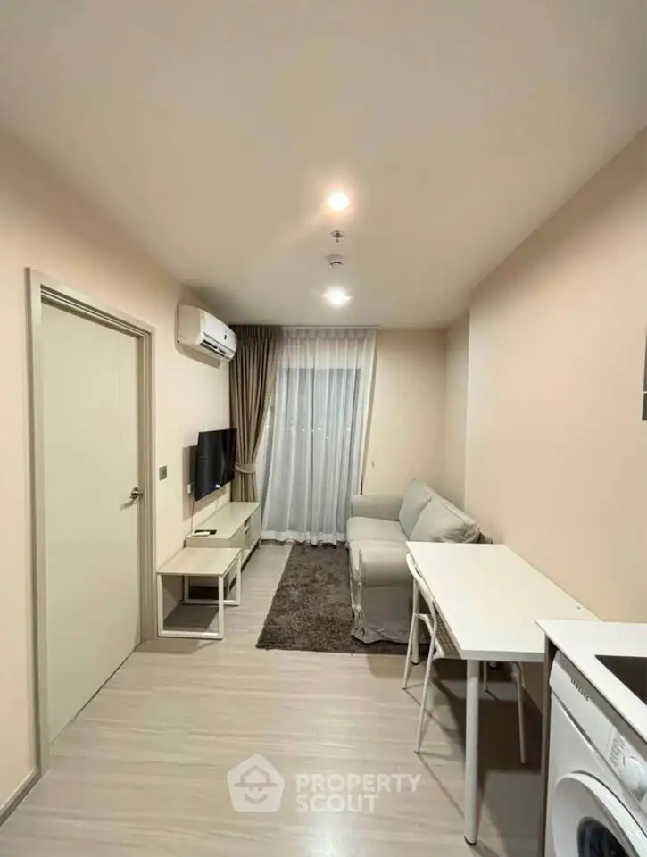 Modern living room with cozy sofa, TV, and dining area in a compact apartment setting.