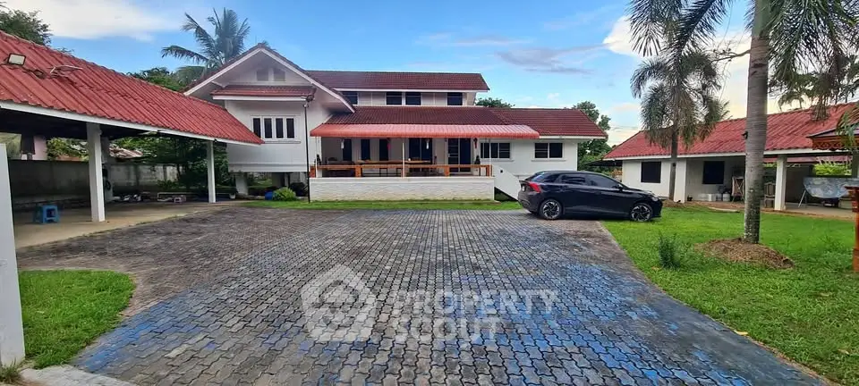 Charming suburban home with red roof, spacious driveway, and lush green lawn.