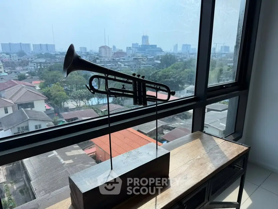 Stunning city view from modern apartment window with decorative trumpet sculpture.