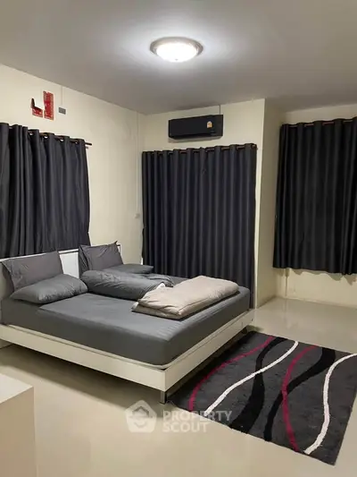 Modern bedroom with sleek design and dark curtains, featuring a cozy bed and stylish rug.