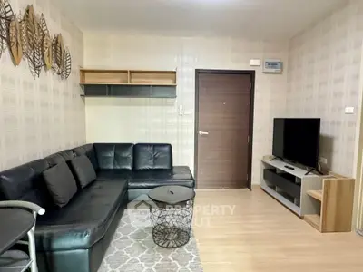 Modern living room with sleek black leather sofa and flat-screen TV, perfect for relaxation.