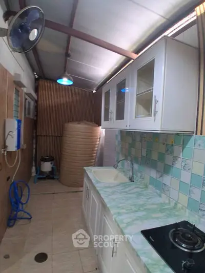 Compact kitchen with gas stove and storage, featuring a unique water tank setup.