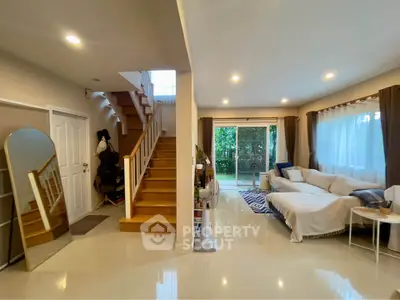 Spacious living room with modern staircase and garden view, perfect for family gatherings.