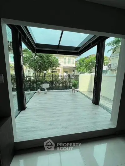 Spacious modern patio with glass roof and garden view, perfect for relaxation and outdoor gatherings.
