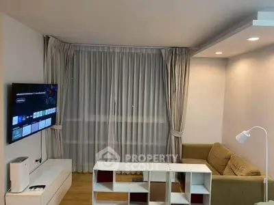 Modern living room with cozy sofa, wall-mounted TV, and stylish curtains.