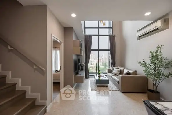 Spacious modern living room with high ceilings and city view, featuring elegant decor and natural light.